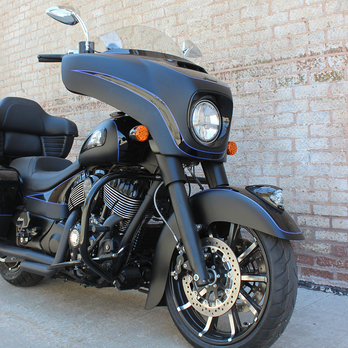 Black custom Indian Chieftain motorcycle on light brick wall