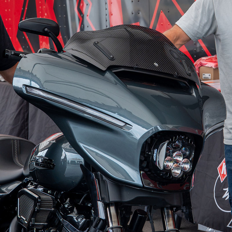Close-up of a Harley-Davidson front fairing and windscreen with a carbon-fiber Flare® Windshield, shown in a real environment. (8" Carbon Fiber)