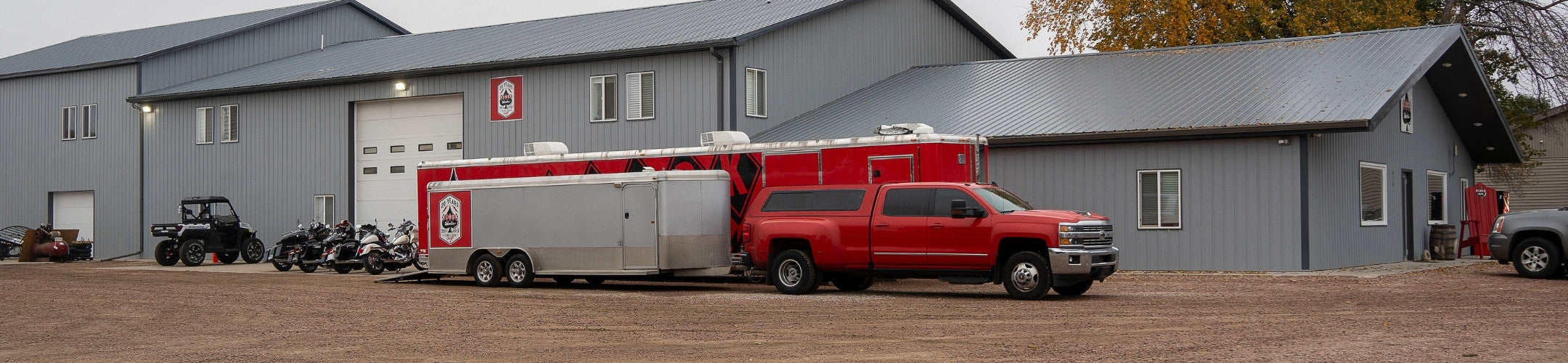 Red truck and Klock Werks trailer parked in front of Klock Werks, a gray shop building.