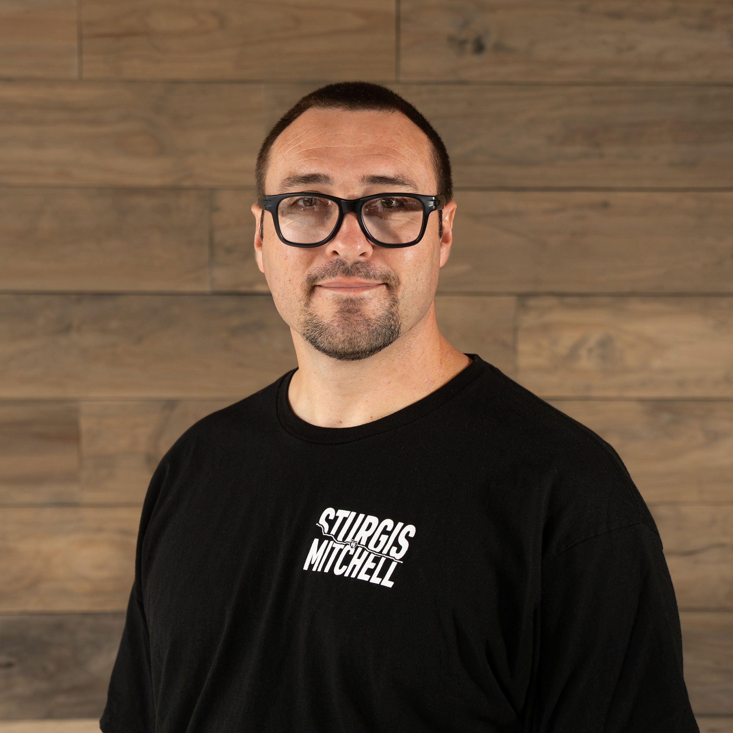 Klock Werks employee Donald Nay standing against a wooden backdrop