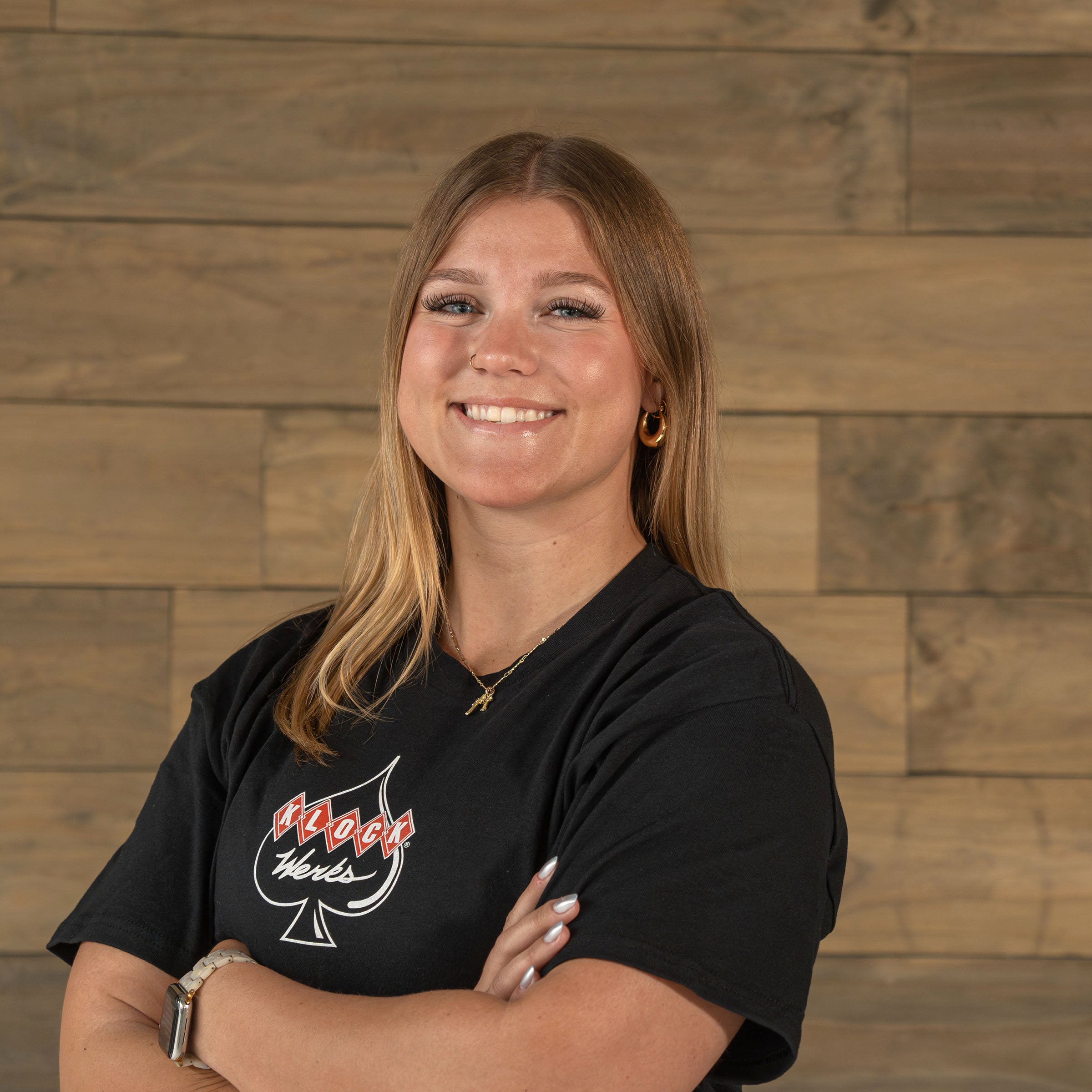 Reagan Grossi poses against a wooden backdrop for her Klock Werks employee photo in Mitchell South Dakota.