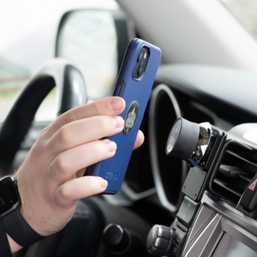 Hand holding a phone in blue OtterBox phone case with an iOdisc magnetically attaching to a ProClip car mount in a vehicle (Universal iOauto for ProClip Vehicle Dash Mounts)