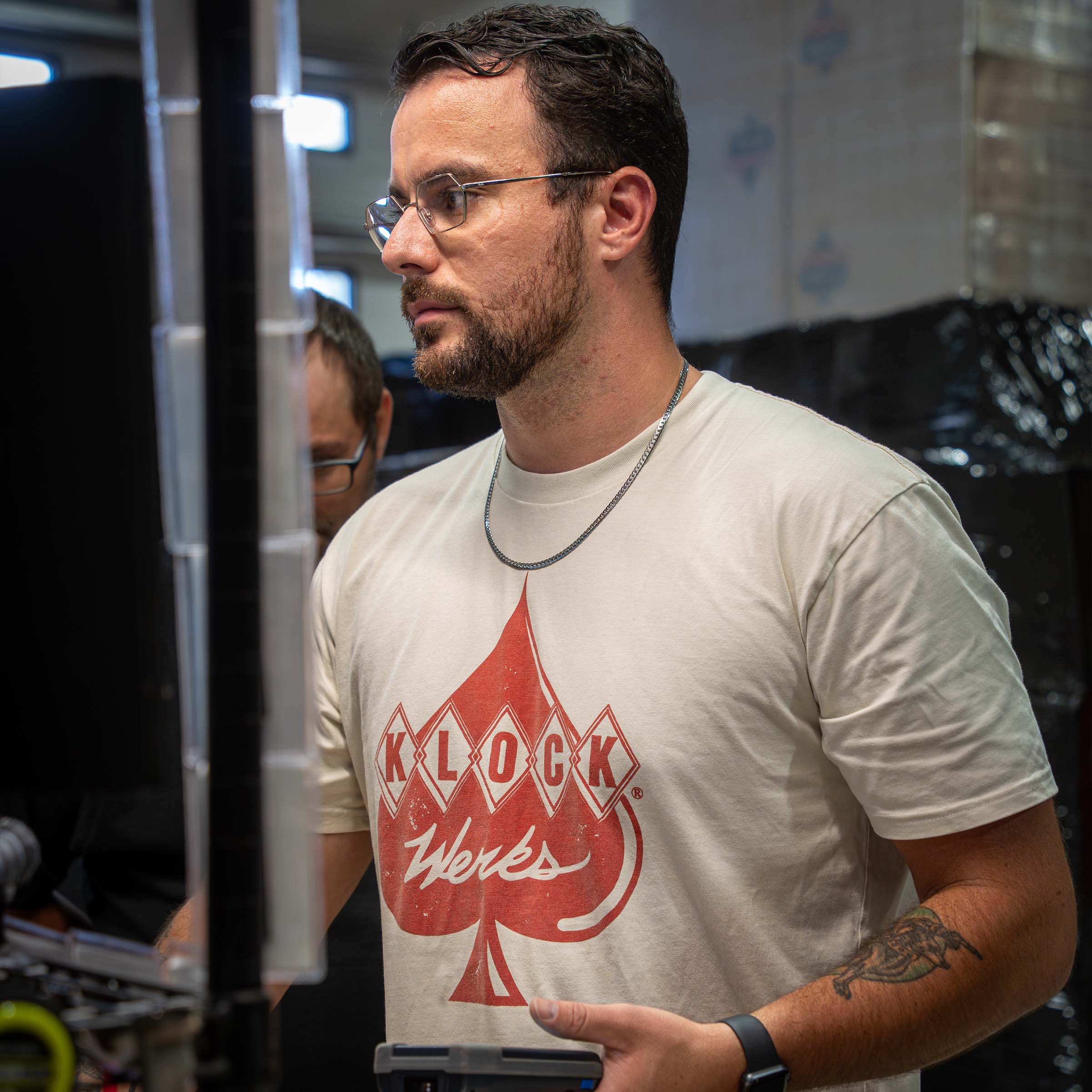 Klock Werks Employee Working in Warehouse Wearing a Klock Werks Red Ink Logo on a Cream Colored T-Shirt