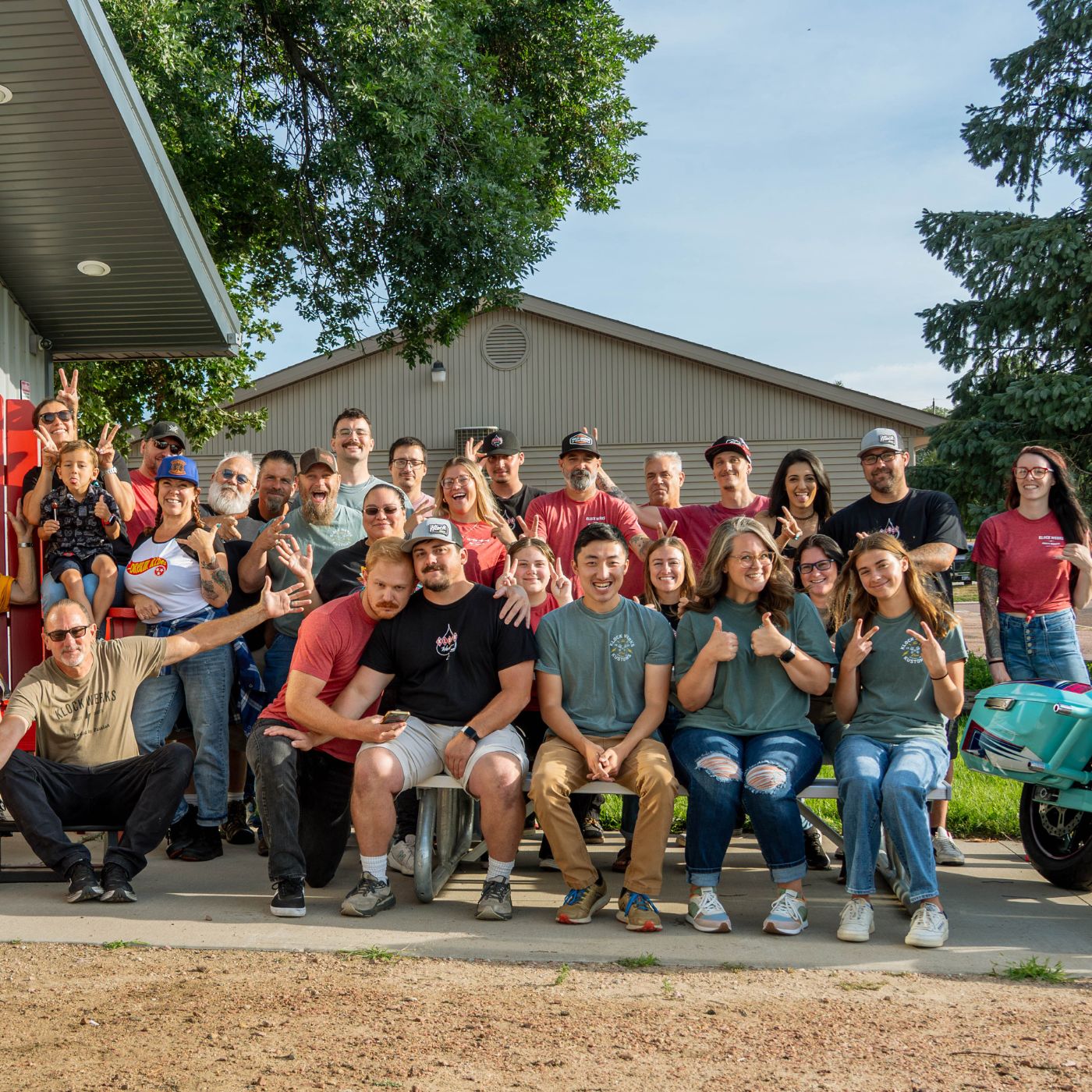 Klock Werks Krew: Picture featuring the employees of Klock Werks out front of their shop in Mitchell South Dakota. Everyone is happy and making silly faces, looking like they are having fun.